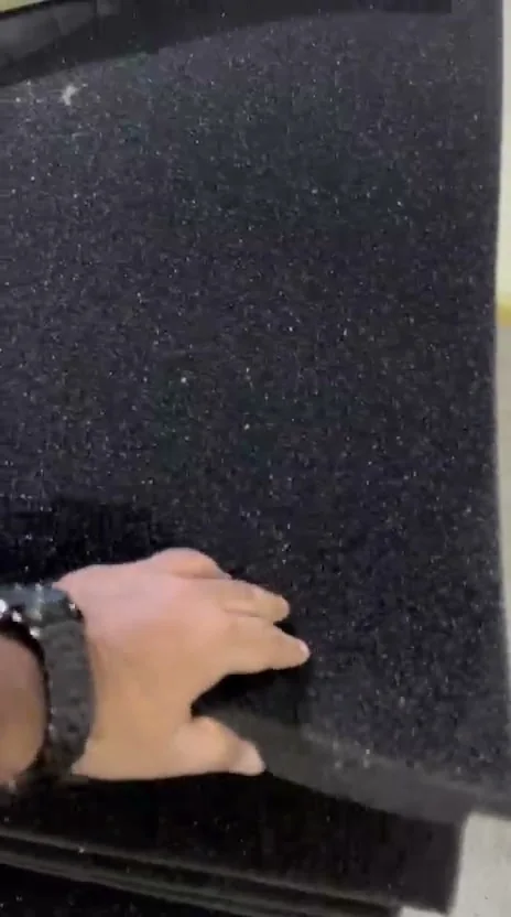 Close-up of a hand on the surface of a reticulated foam sheet showing the open-cell strand structure